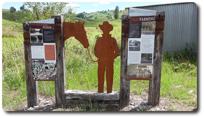Two signs and worker siloette in front of rail line