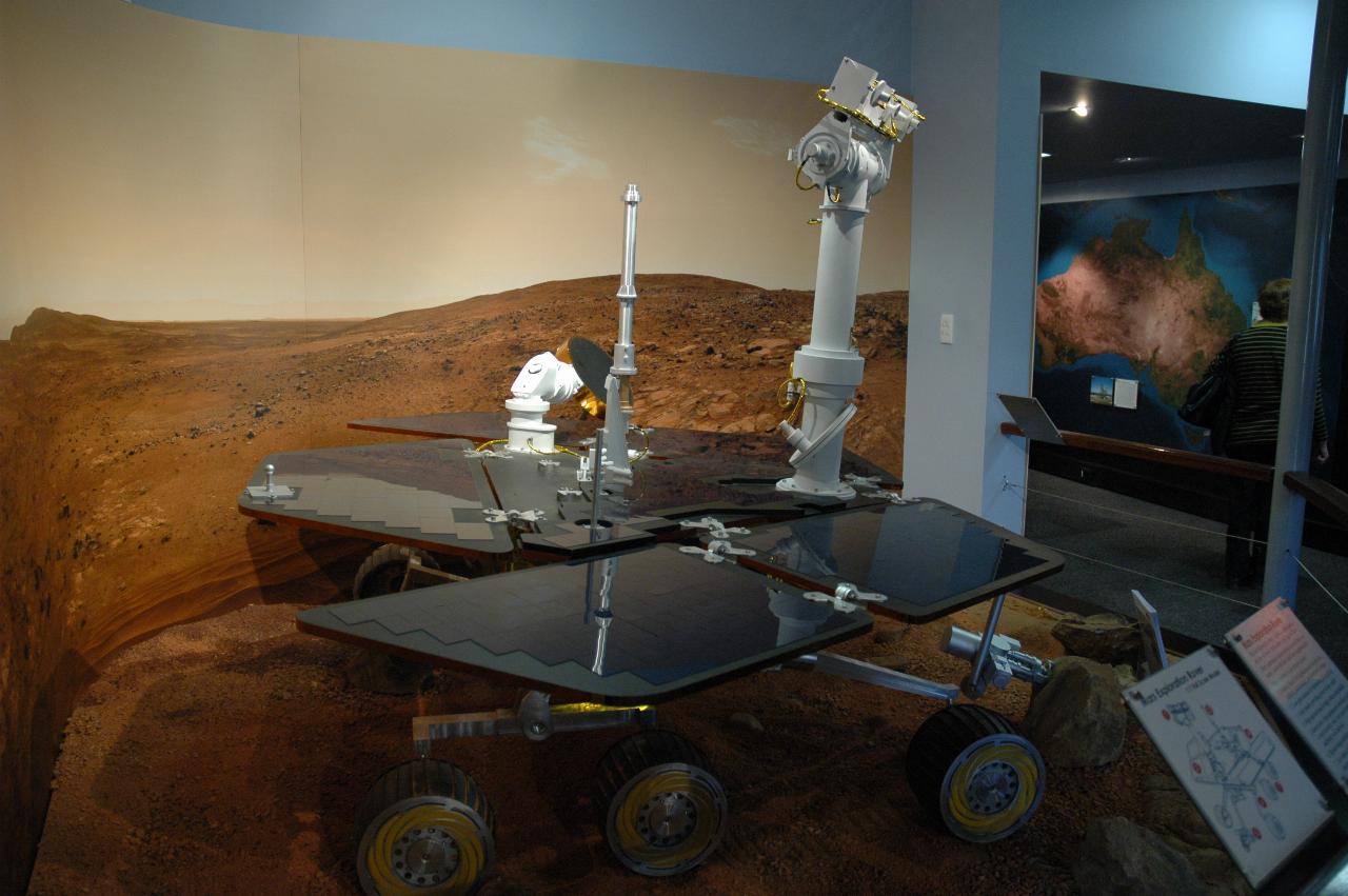 Mars rover in display of simulated surface of Mars; side view