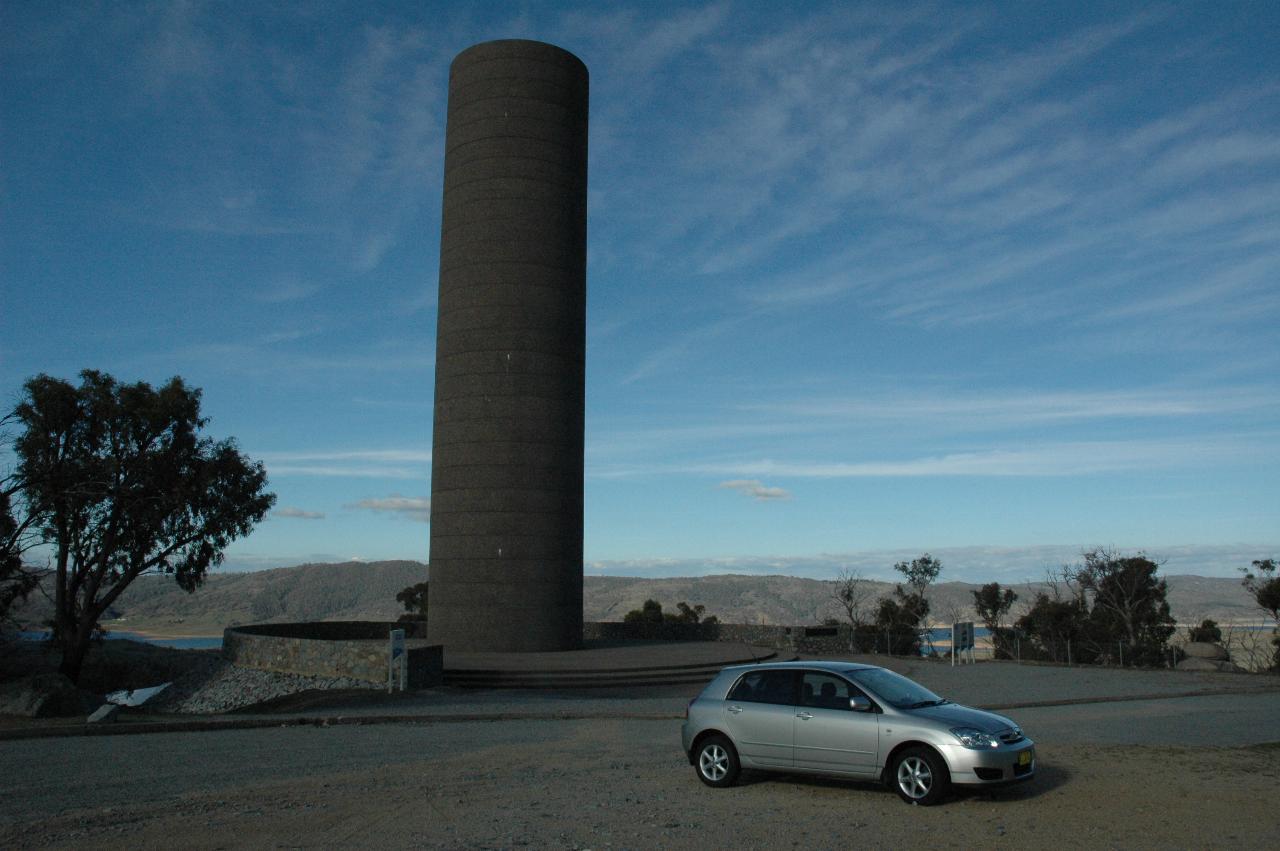 Car parked in front of tall cement cylinder