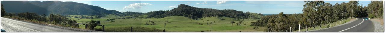 Panorama from mountains, over green pasture to ocean